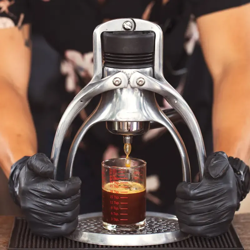 Man pressing down on his manual espresso maker and espresso being squeezed out of it