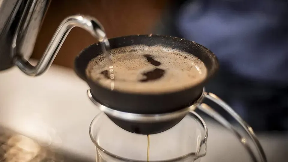 Pouring hot water over coffee in a ceramic coffee filter