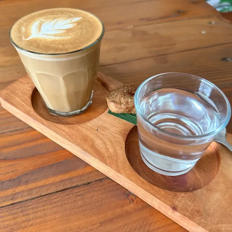 Side view of a piccolo latte and a glass of water with a cookie
