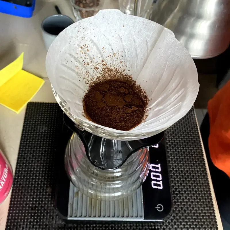Pour over methos shown with a carafe and a pour over coffee maker - close up on the coffee ground inside the filter