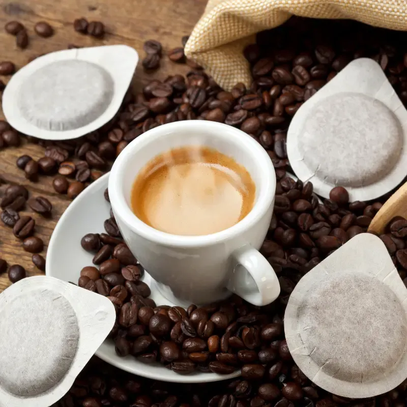 Paper coffee pods with coffee beans and an espresso cup