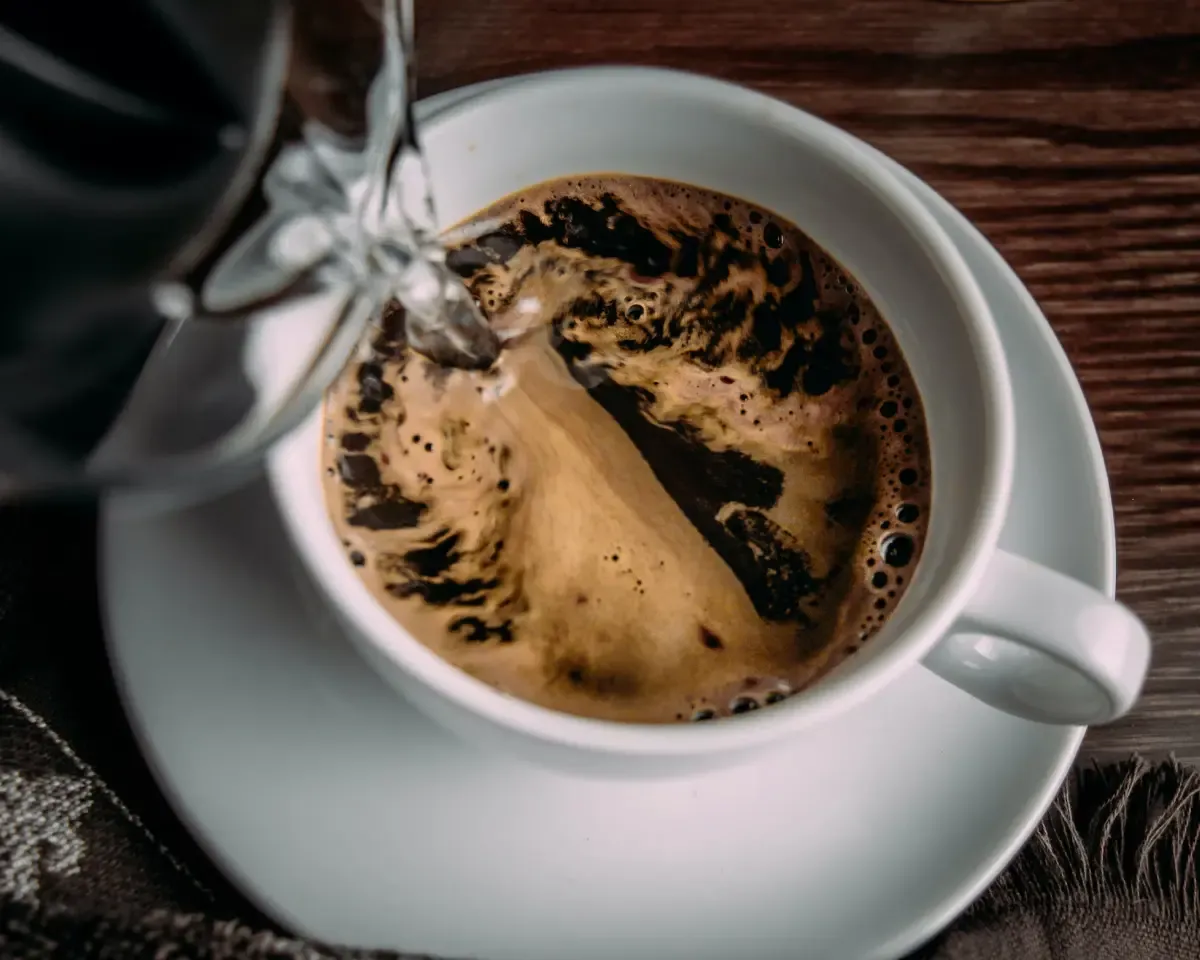 Cup of powder coffee with hot water being poured over