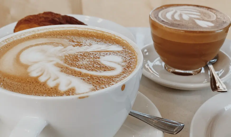 A cup of latte with a cup of cortado and a croissant