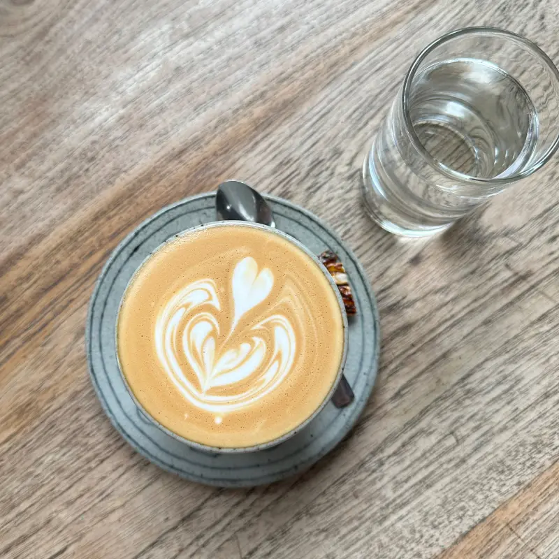 Piccolo latte top view with a snack and a glass of water