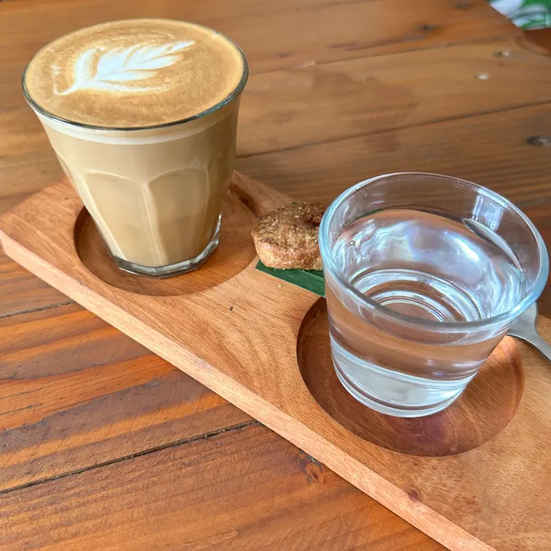 Side view of a piccolo latte and a glass of water with a cookie