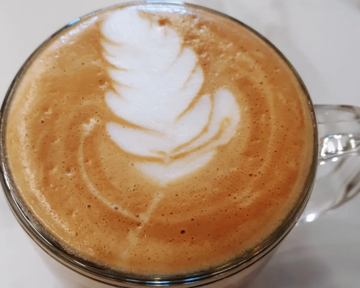 Cup of latte with a feather drawing