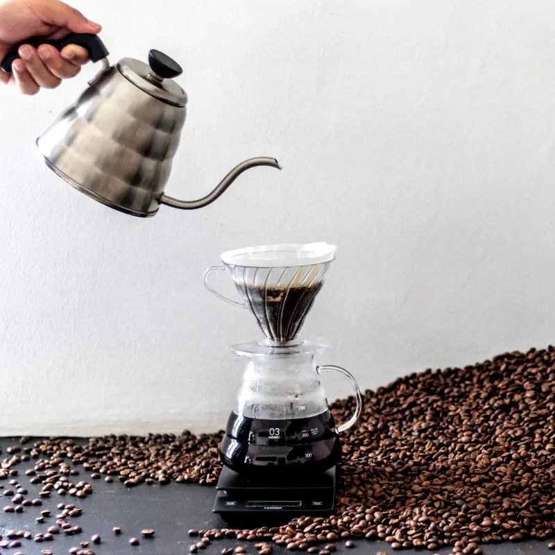 kettle pouring boiled water over coffee beans in a conical filter