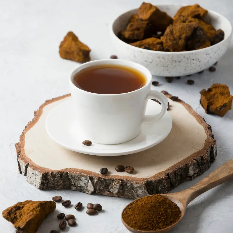 Mushroom coffee in a white cup with a bowl of chaga in the background