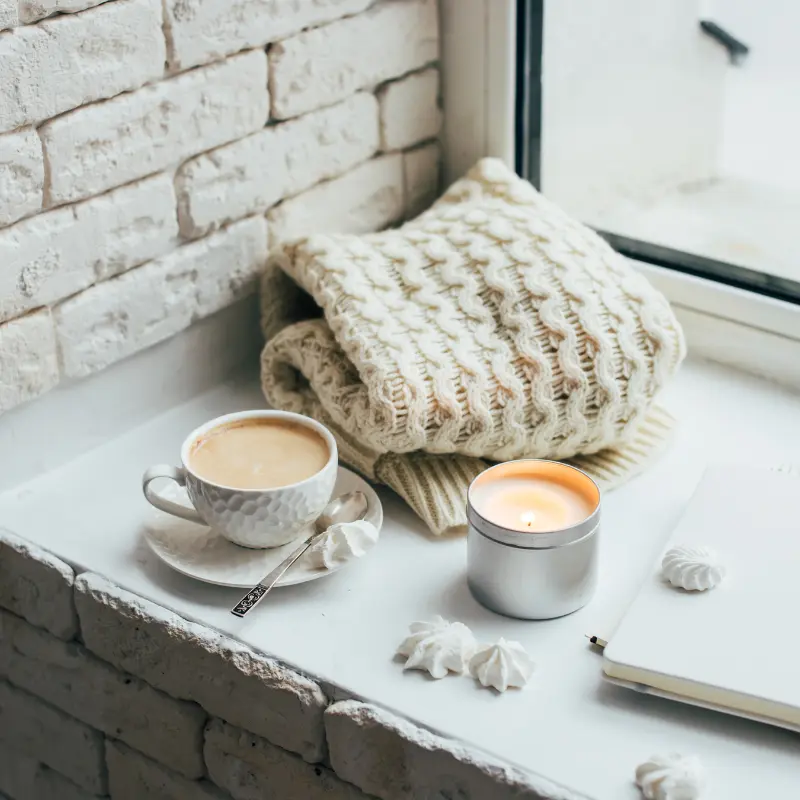 Cup of coffee with sweater and a candle